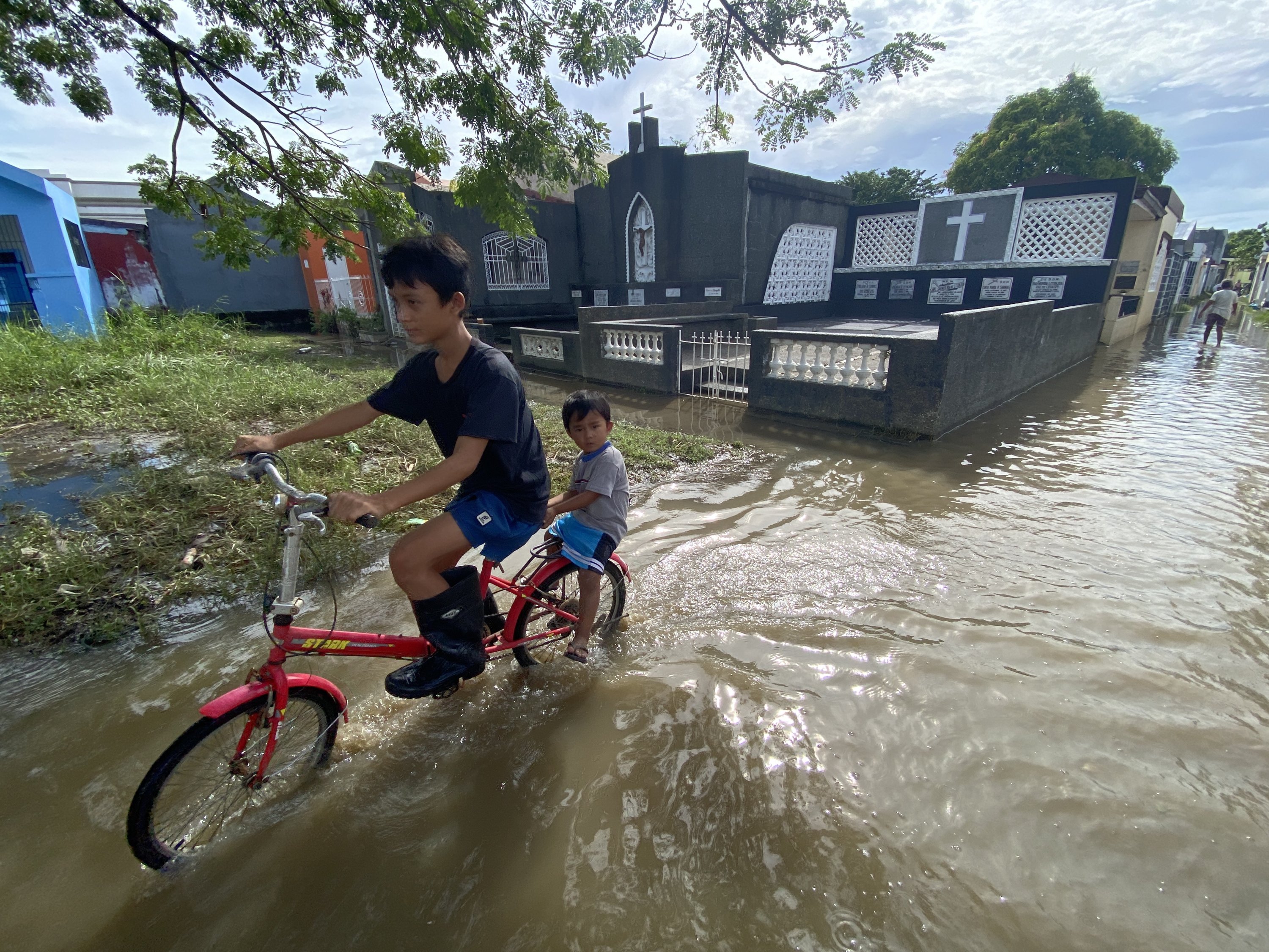 Filipinli çocuklar, su basmış bir mezarlıkta bisiklet sürüyorlar, Cavite, Filipinler, 31 Ekim 2022. (EPA Fotoğrafı)