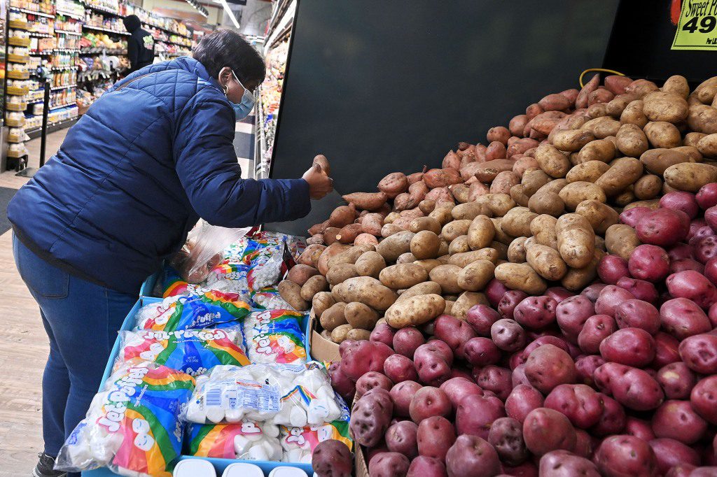 Bir kadın bakkalda patates dağıtıyor.