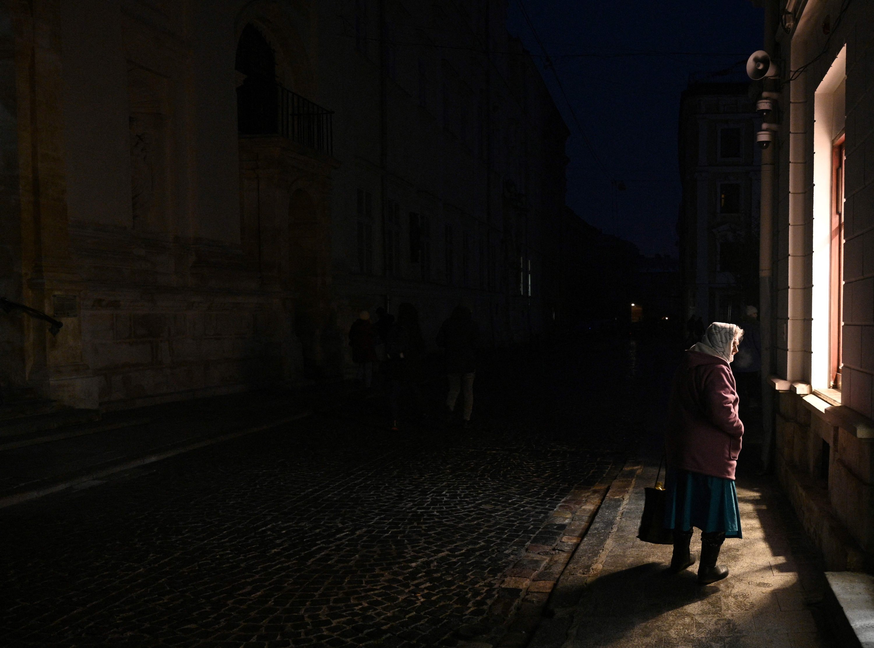 Ukrayna'nın Lviv kentinde Rus saldırılarının ardından elektrik kesintisi sırasında sokakta yürüyen bir kadın, 23 Kasım 2022. (AFP Fotoğrafı)