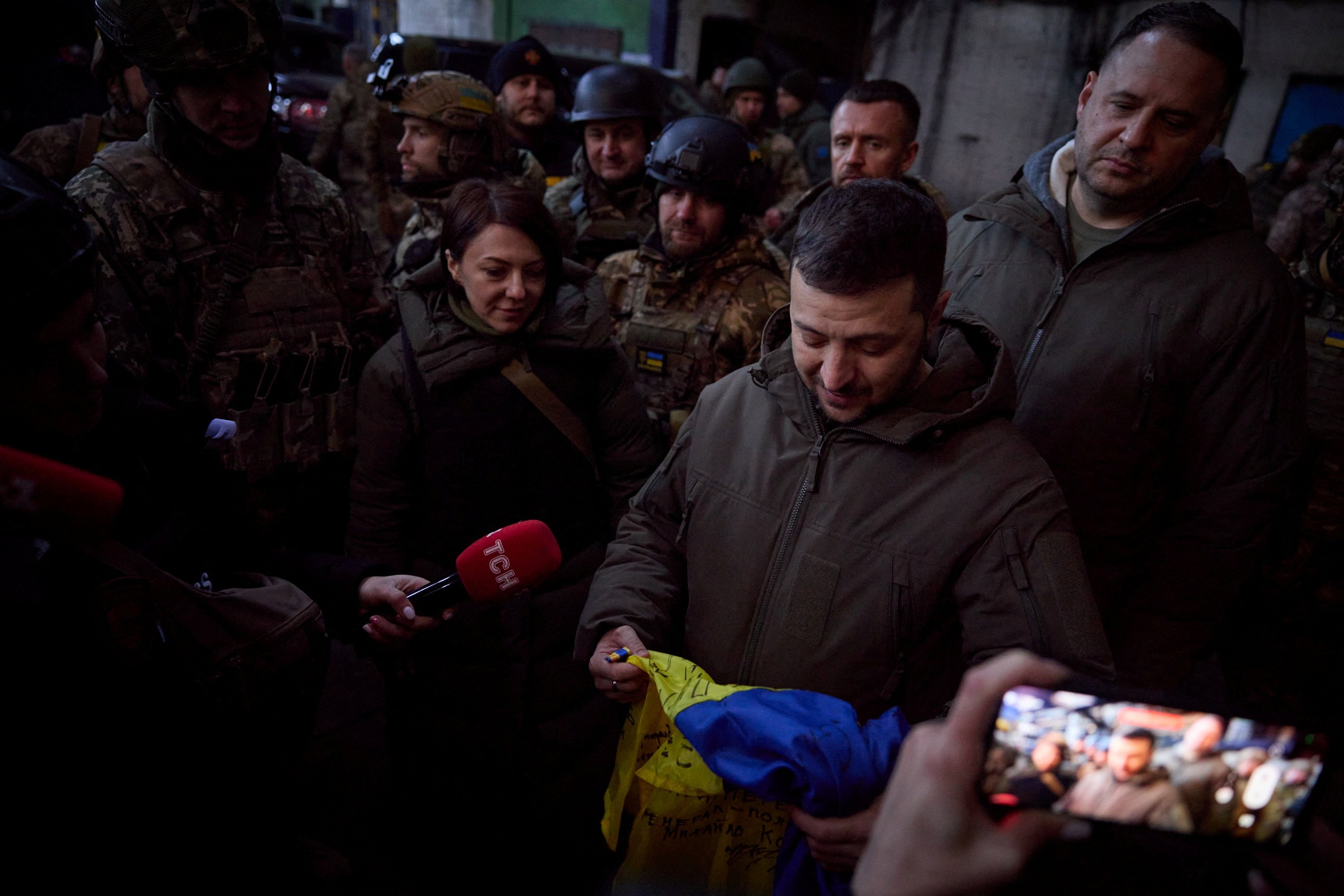 Ukrayna Devlet Başkanı Volodymyr Zelenskyy, 20 Aralık 2022, Ukrayna'nın Donetsk bölgesi, Bakhmut'ta Ukraynalı askerleri ziyaret ederken elinde bir bayrak tutuyor. (Reuters Fotoğrafı)