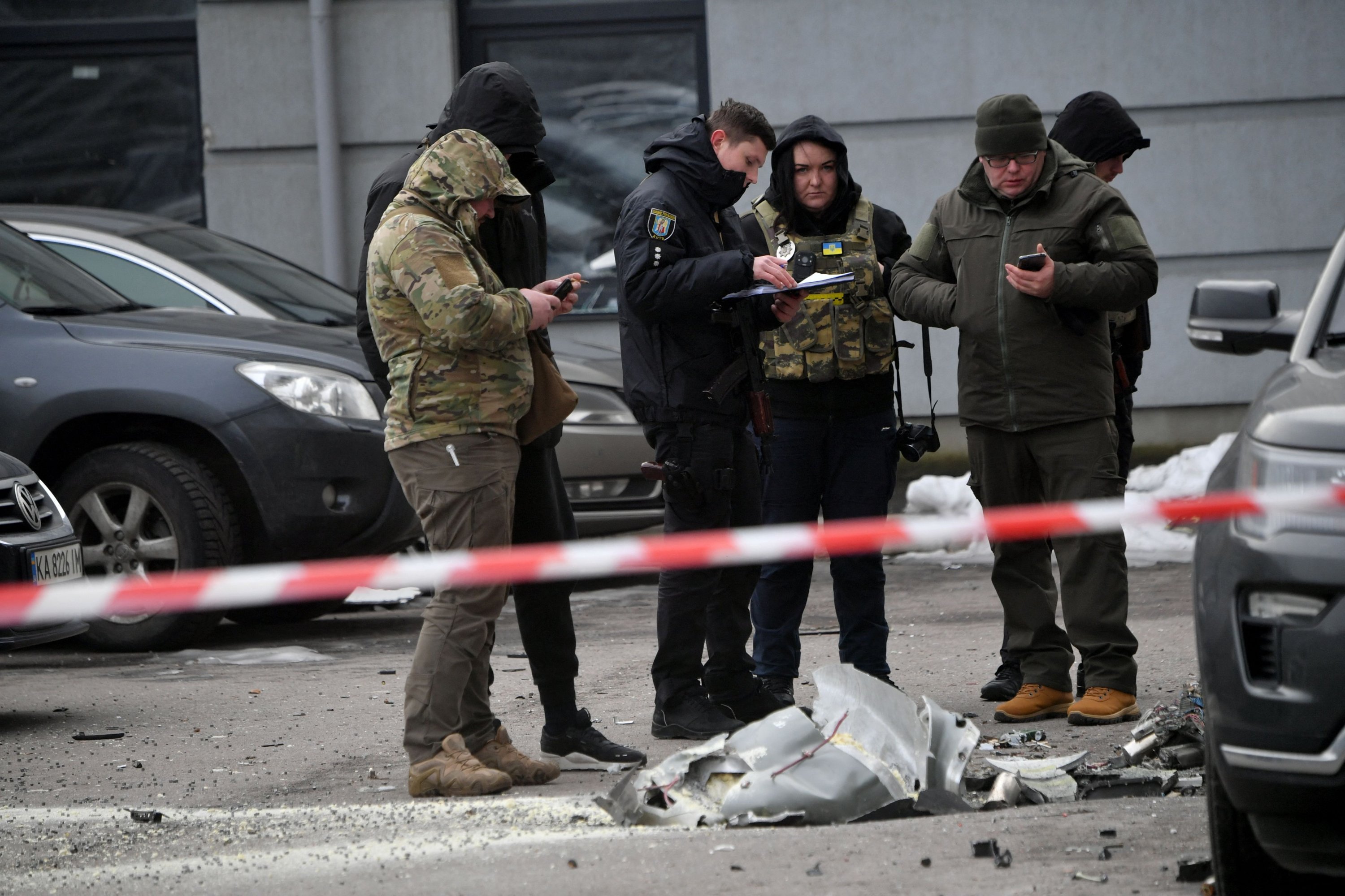 Polis uzmanları, çok katlı bir konut binasına park etmiş araçların üzerine düşen düşürülen bir füzenin kalıntılarını inceliyor, Kiev, Ukrayna, 29 Aralık 2022. (AFP Fotoğrafı)