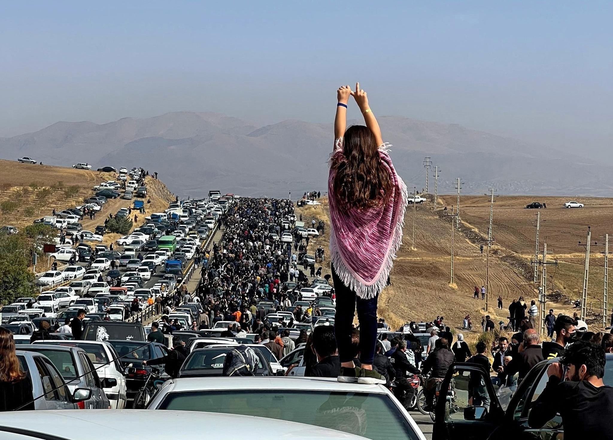 Binlerce kişi Mahsa Amini'nin mezarına doğru ilerlerken bir aracın tepesinde duran bir kadın, Saqez, İran, 26 Ekim 2022. (AFP Fotoğrafı)