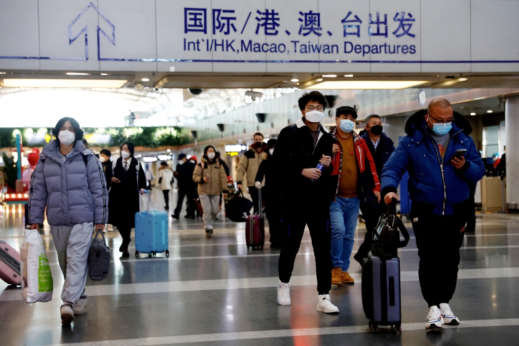 Gezginler Pekin Başkent Uluslararası Havalimanı'nda bagajlarıyla birlikte yürürler.