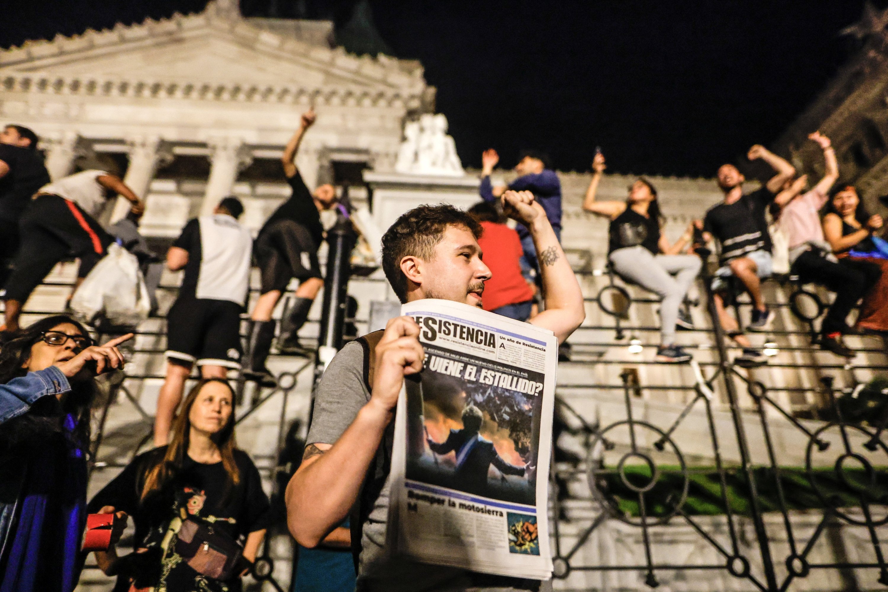 İnsanlar Arjantin Devlet Başkanı Javier Milei tarafından Buenos Aires, Arjantin'deki Ulusal Kongre önünde açıklanan tedbirlere karşı düzenlenen gösteriye katılırken bir protestocu elinde gazete var, 21 Aralık 2023. (EPA Fotoğrafı)