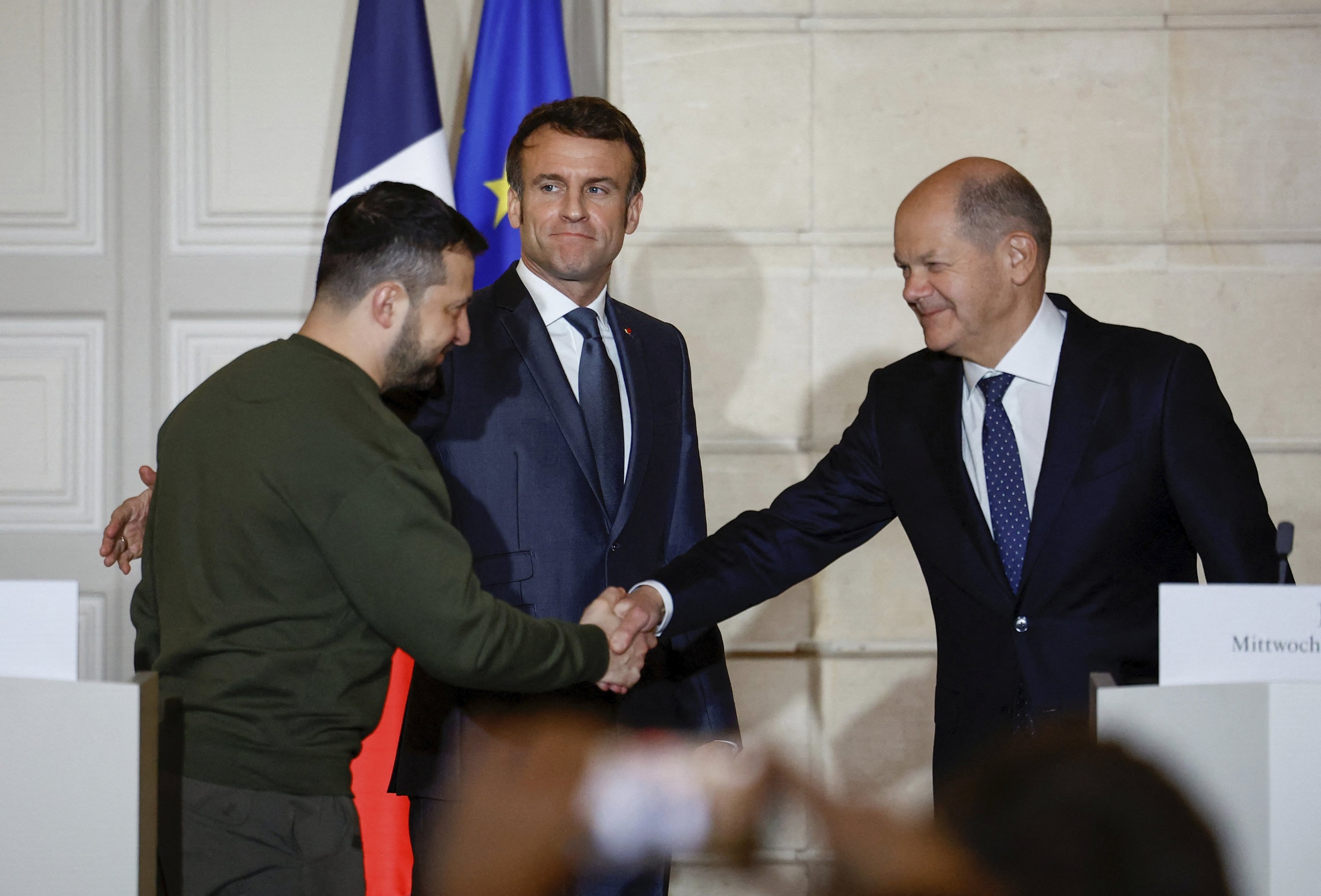 Fransa Cumhurbaşkanı Emmanuel Macron (C), Ukraynalı mevkidaşı Volodymyr Zelenskyy'yi (L) Almanya Başbakanı Olaf Scholz ile Elysee Sarayı, Paris, Fransa'da düzenlenen ortak basın toplantısında el sıkışırken izliyor, 8 Şubat 2023. (AP Fotoğrafı)