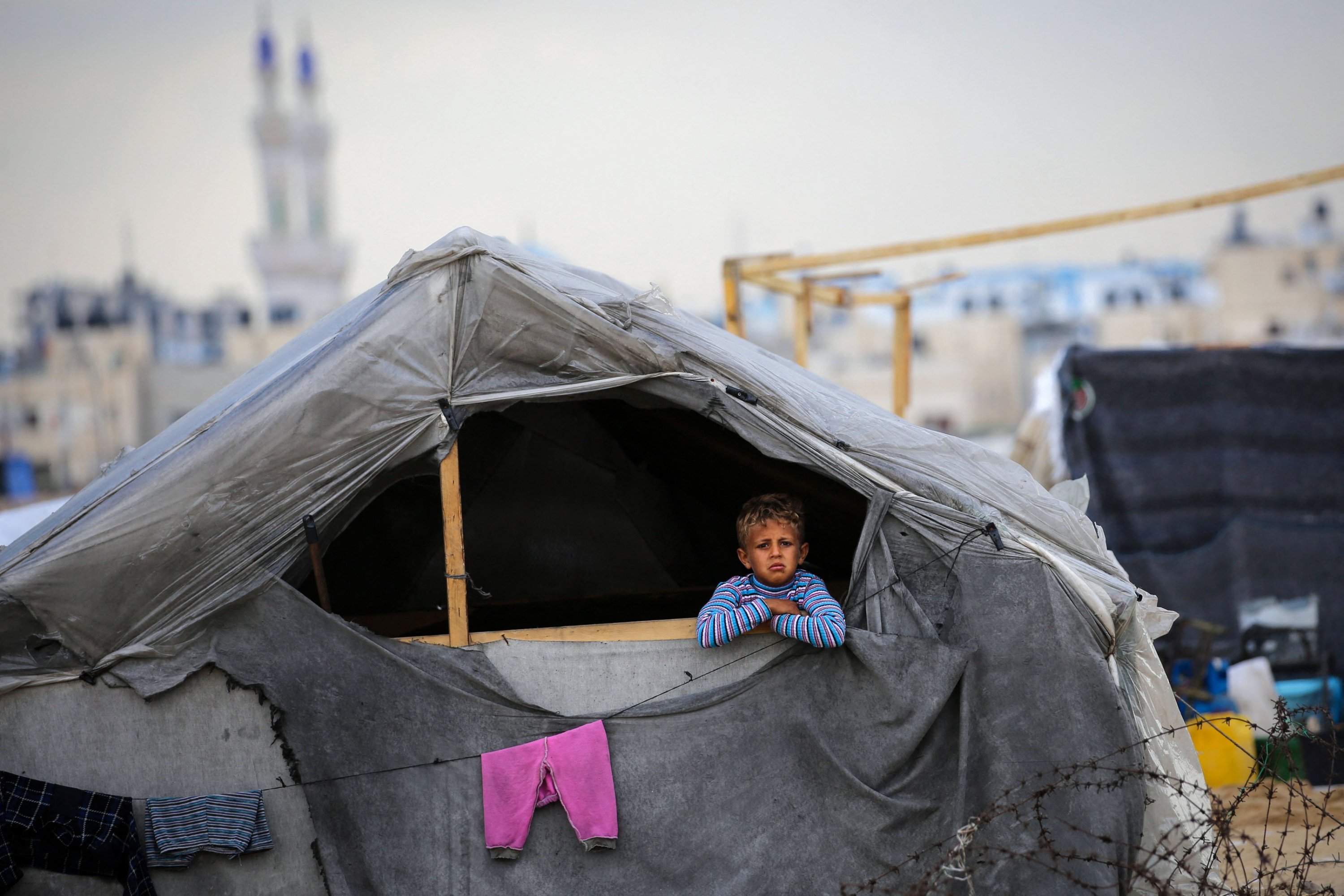 Filistinli bir çocuk, Gazze Şeridi'nin güneyindeki Refah mülteci kampındaki çadırından dışarı bakıyor, Filistin, 13 Mayıs 2024. (AFP Fotoğrafı)